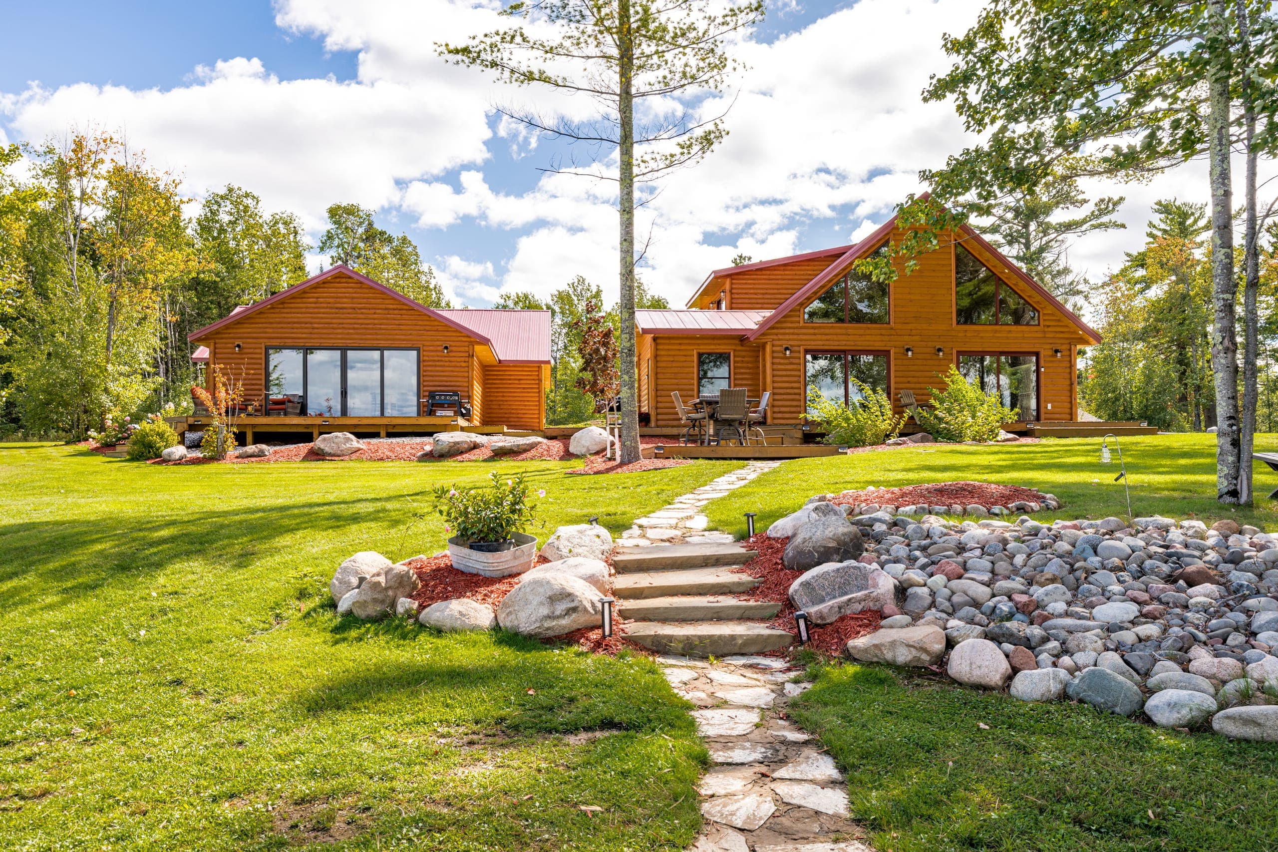 Both cabins across the lawn, with a stone path in the foreground
