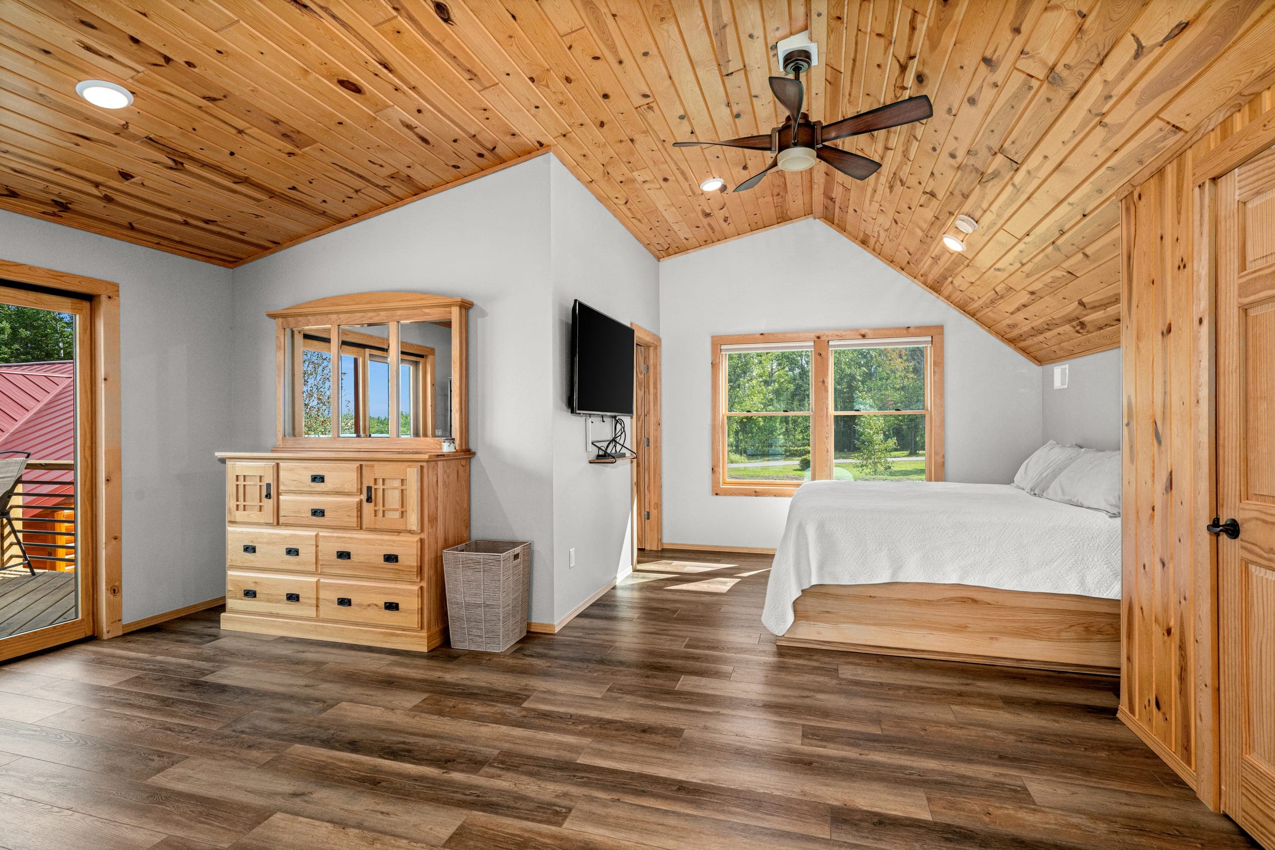 Bedroom with white linens under a vaulted pine ceiling
