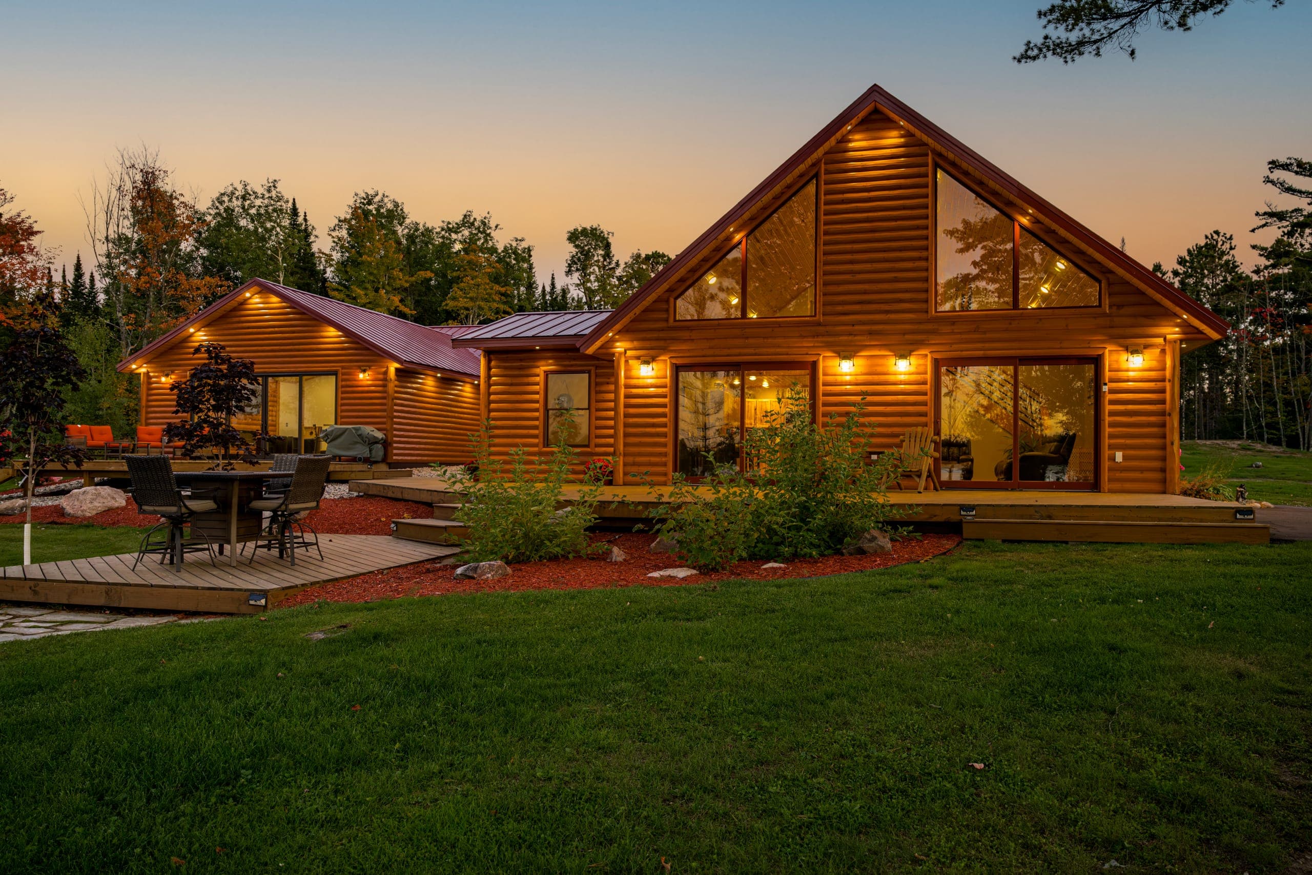 Main cabin glowing at dusk, with the great room windows lit