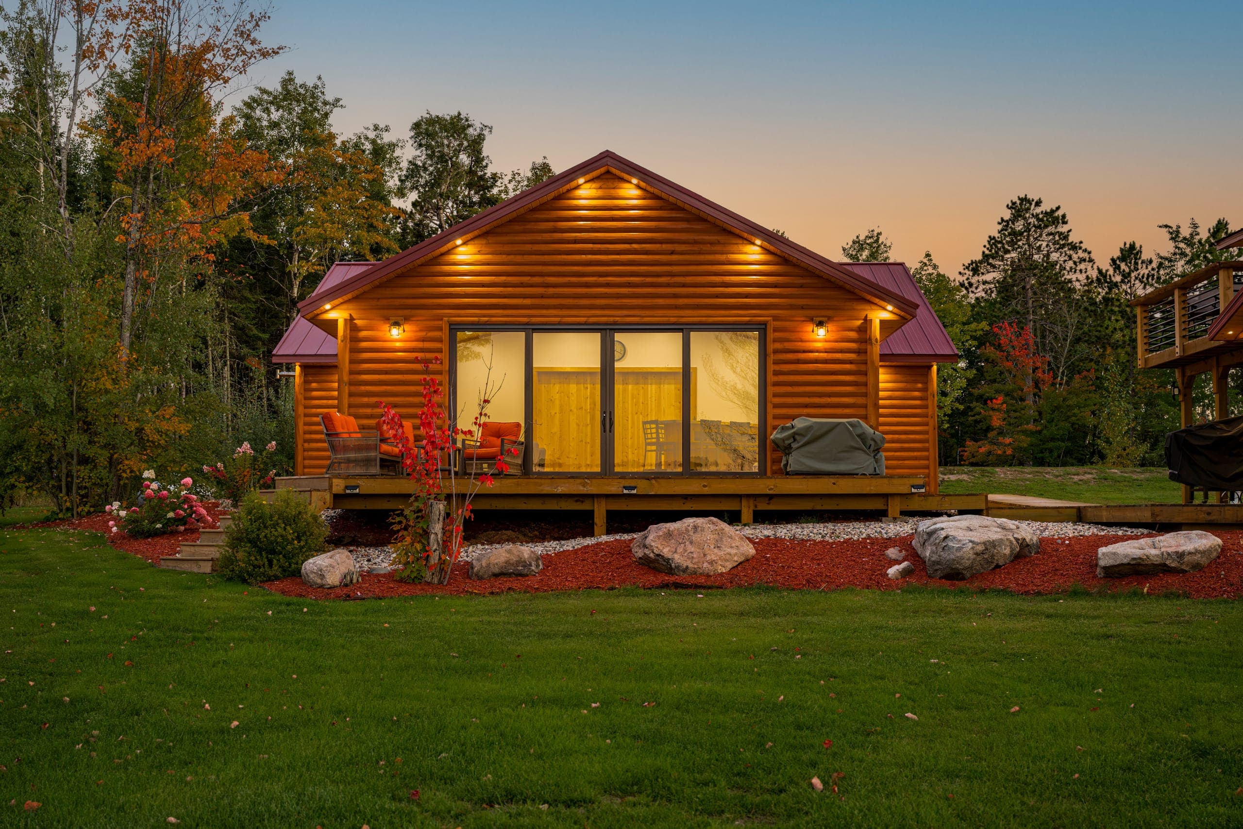 Guest cabin lit at dusk, with chairs on the deck