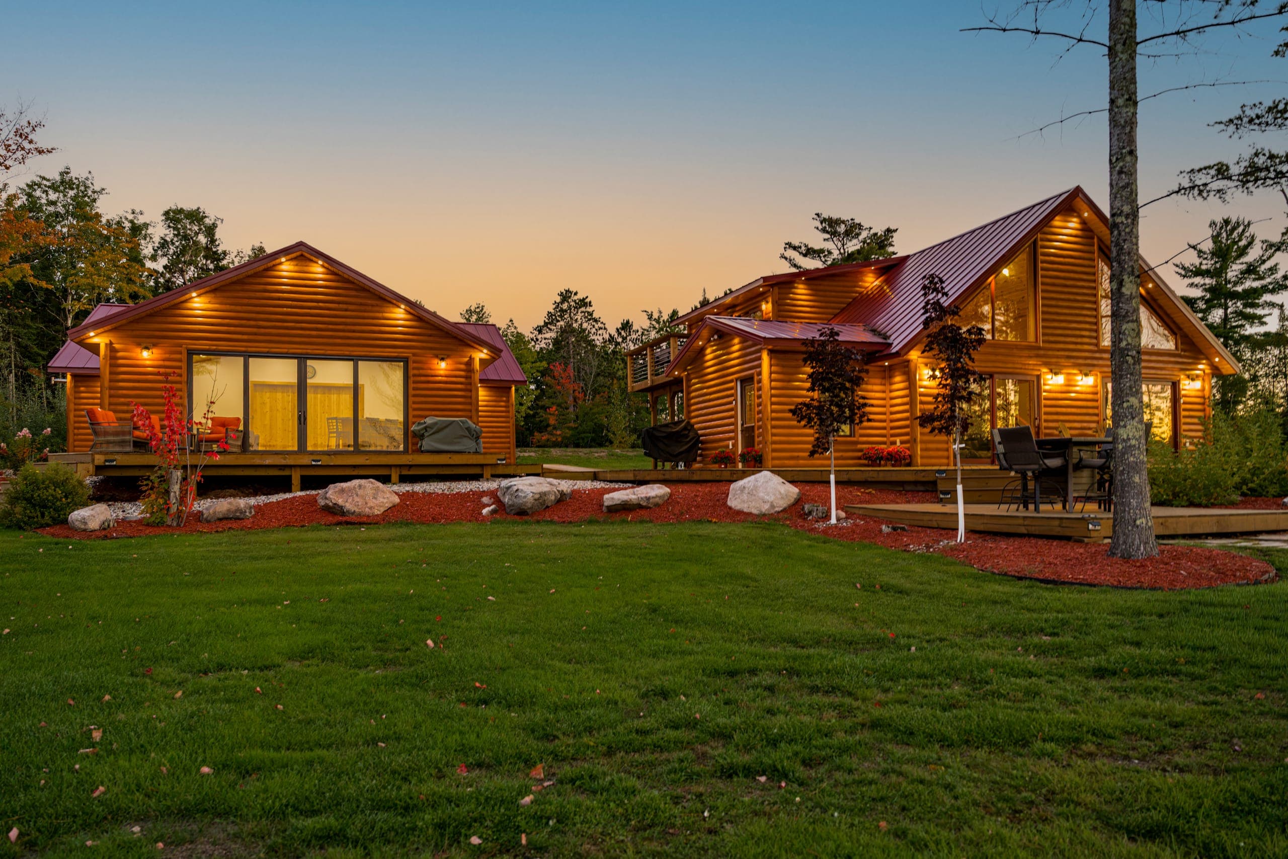 Both cabins lit at dusk across the lawn