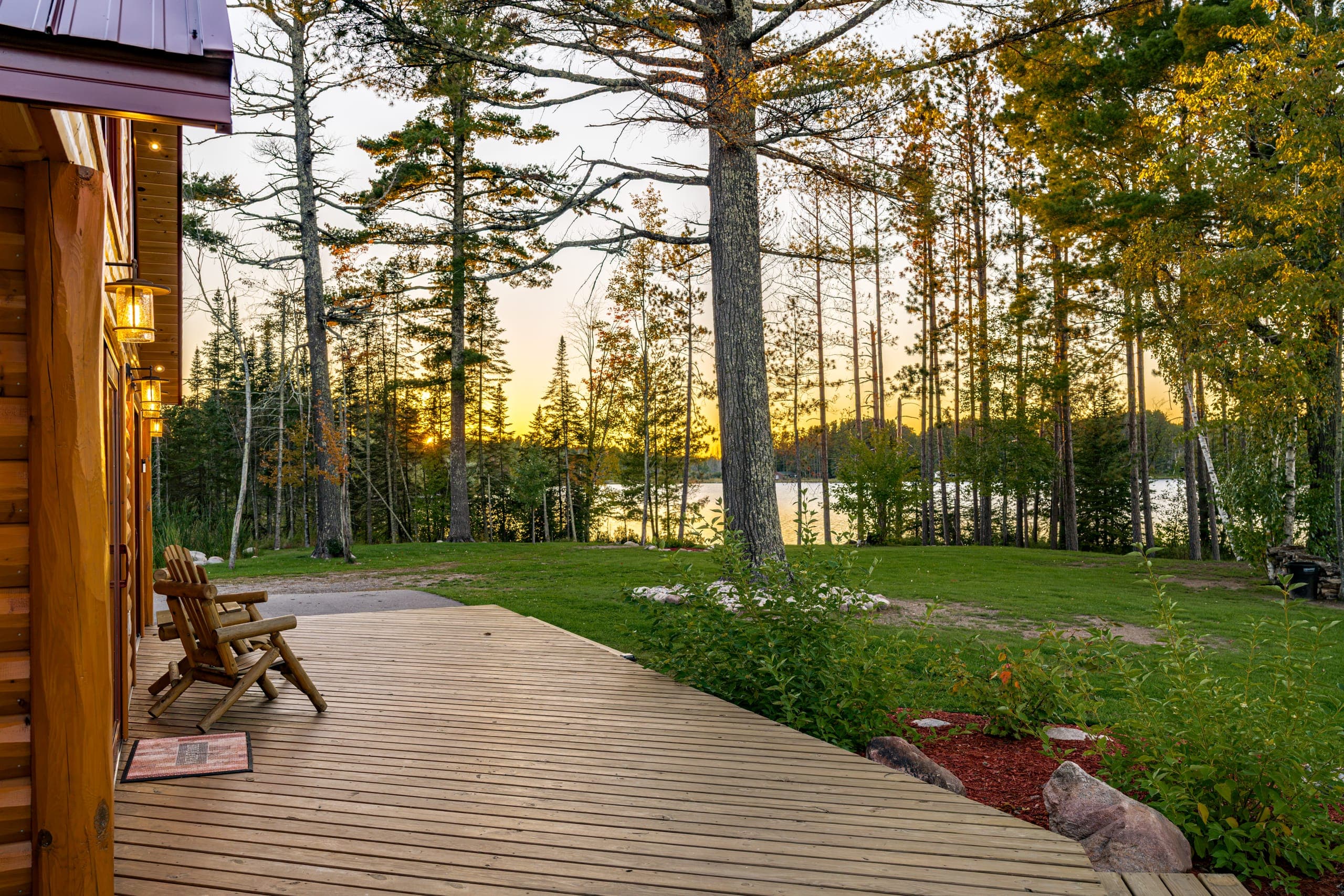 Chairs on the deck facing the sunset through the pines