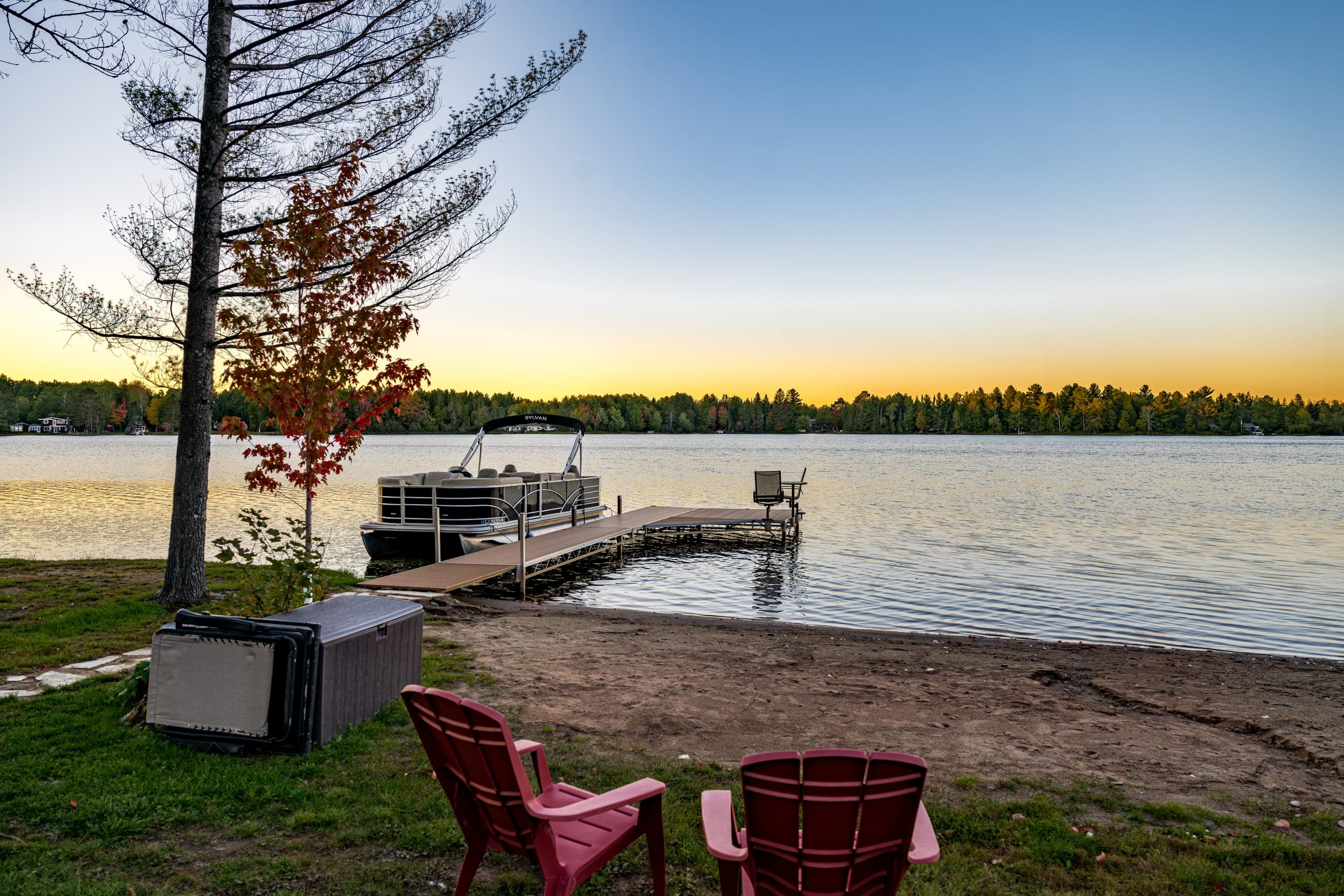 Adirondack chairs on the beach, dock in the distance