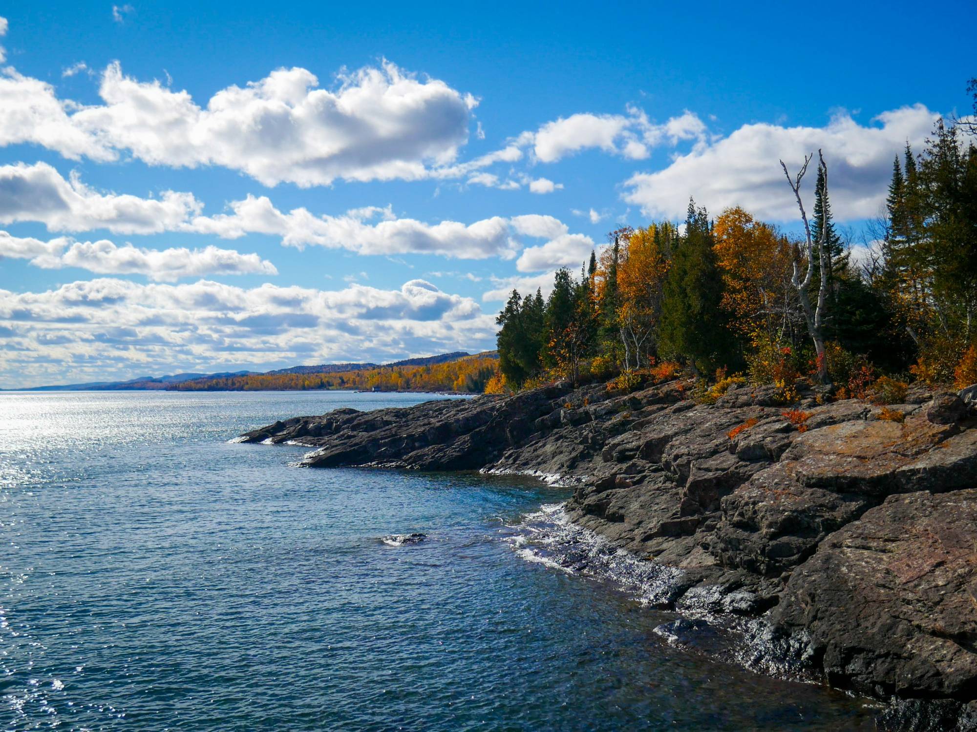 Lake Superior's rocky shore in fall color, with the hills of the North Shore beyond